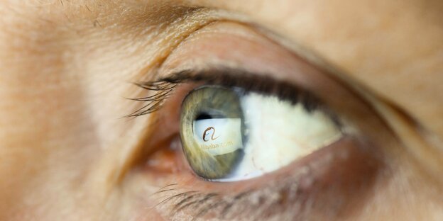 Auf der Linse eines menschlichen Auges spiegelt sich das Alibaba-Logo