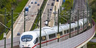 Ein ICE fährt über einer Brücke über der Autobahn