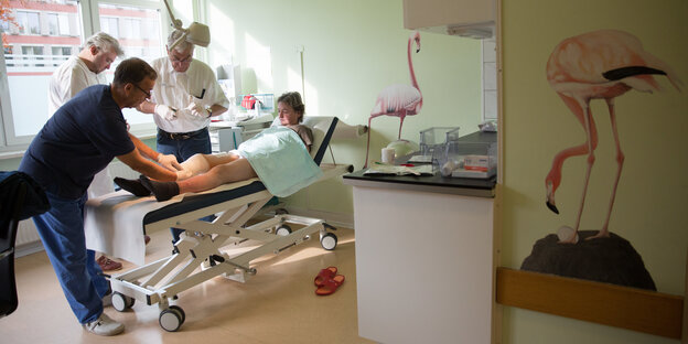 Zwei Ärzte und ein Pfleger versorgen eine Patientin in der Krankenstube auf St. Pauli.