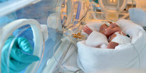 Ein frühgeborenes Kind liegt in einem Inkubator.