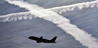 Ein Flugzeug vor zwei sich kreuzenden Kondensstreifen am blauen Himmel