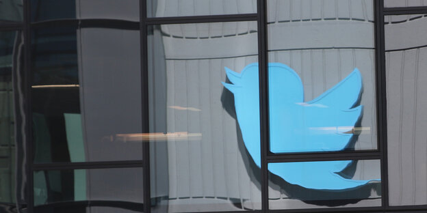 Der blaue Vogel, das Twitter-Logo, spiegelt sich in einer Fensterfassade
