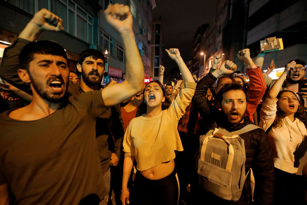 Demonstrierende protestieren mit gereckten Fäusten und regierungskritischen Rufen