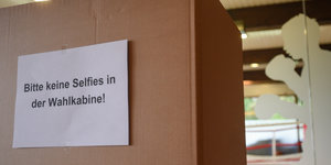 Ein Zettel mit der Aufschrift „Bitte keine Selfies in der Wahlkabine“ hängt an der Kabine des Wahllokals.