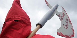 Mensch von hinten mit roter Kapuze und einem Beil in der Hand