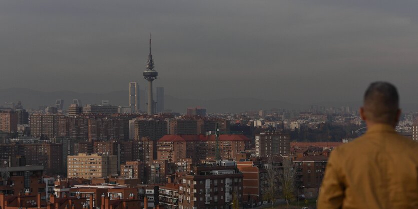 Ein Mann schaut von einer Aussichtsplattform auf die Dächer Madrids.