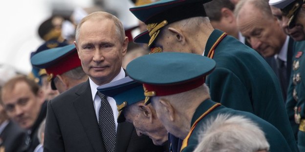 Ältere Männer in Uniform neben Wladimir Putin