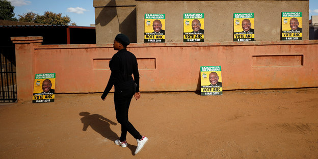 Eine Frau läuft an ANC-Wahlplakaten vorbei