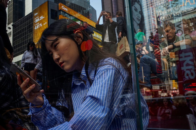 Am Times Square in New York Citx blicken Menschen auf ihr Smartphone