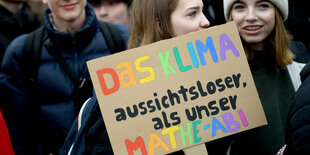 Schülerin hält Plakat "Das Klima, aussichtsloser als unser Mathe-Abi"