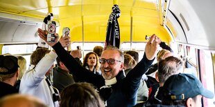 Ein Fan von Eintracht Frankfurt feiert in einem Bus mit anderen Fans