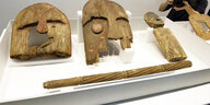 Holzmasken und Stäbe austgestellt auf einer Platte im Museum
