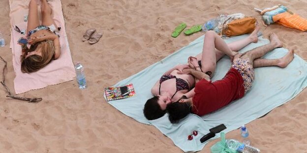Menschen liegen auf Handtüchern auf dem Sand
