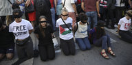 Aktivistinnen knien mit verbundenen Augen auf der Straße