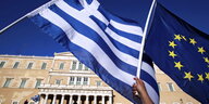 Die griechische Flagge und die EU-Fahne werden vor dem Parlament in Athen hochgehalten