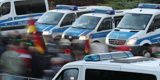 Demonstranten mit Deutschlandfahnen ziehen an Polizeiautos vorbei