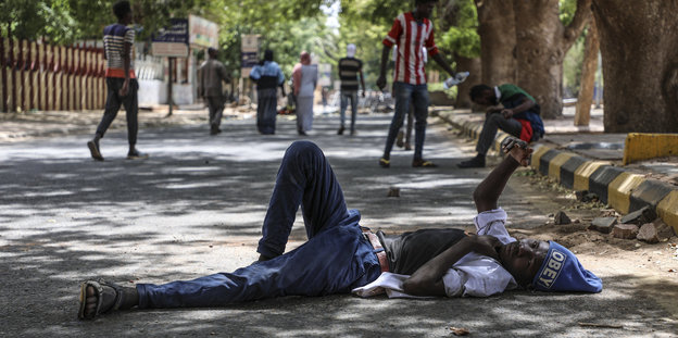 Ein Demonstrant ruht sich auf der Straße liegend aus, die zu der Sit-In-Demonstration vor den Militär-Hauptgebäude führt