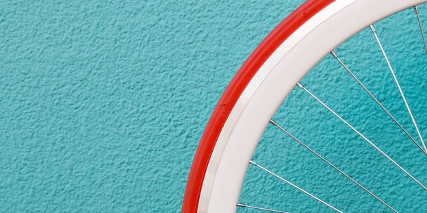 Ornage-weißer Fahrradreifen vor einer türkisen Wand