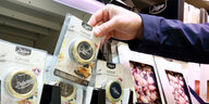 Eine Hand nimmt eine Kaviar-Packung aus dem Kühlregal