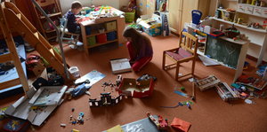 Zwei Kinder spielen in einem unordentlichen Kinderzimmer