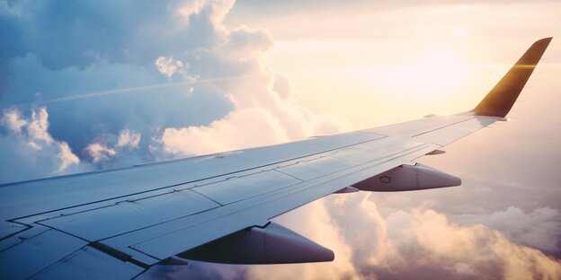 Der Blick aus einem Flugzeug: Wolken und Sonne und ein Flugzeug-Flügel