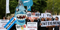 Menschen, davon einer in einem Hai-Kostüm, demonstrieren gegen die Vonovia-Aktionärsversammlung