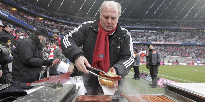 Uli Hoeneß nimmt sich eine Bratwurst im Brötchen