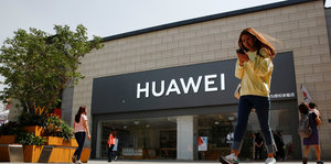 Frau mit Smartphone vor Huawei-Shop