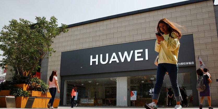 Frau mit Smartphone vor Huawei-Shop