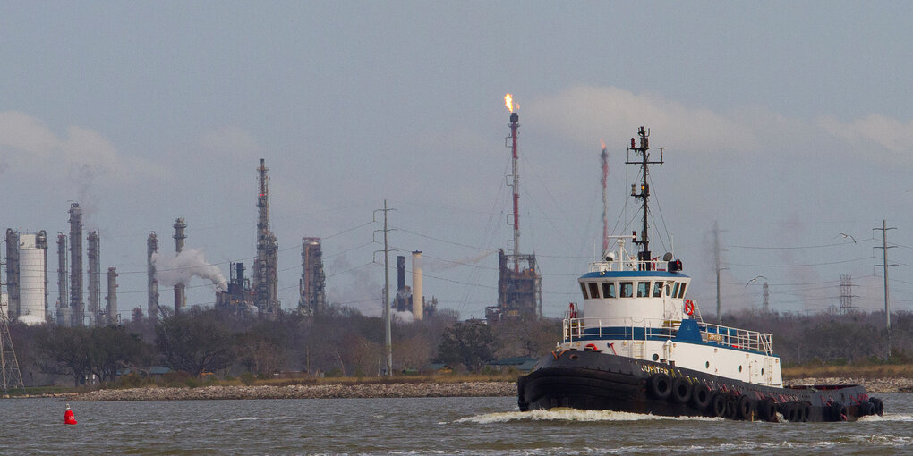 ein Schiff fährt an einer Raffinerie vorbei