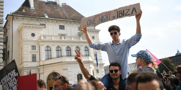 Demo auf dem Ballhausplatz in Wien, ein Mann hält ein Schild hoch mit der Aufschrift "Gib mir nur eine Nacht auf Ibiza" auf englisch