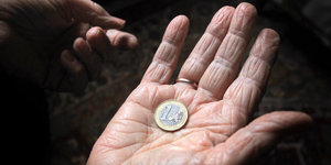 Münze in der Innenfläche einer älteren Hand
