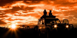 Zwei Frauen auf Auto vor Sonnenuntergang