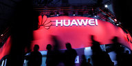 Menschen laufen an einem großen Huawei-Zeichen vorbei