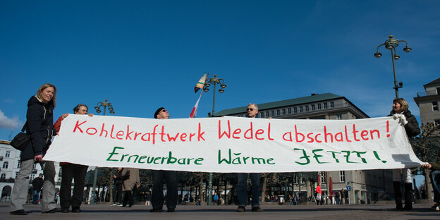 Demonstranten halten ein Plakat mit der Aufschrift: Kohlekraftwerk Wedel abschalten! Erneuerbare Wärme jetzt!