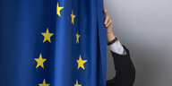 Eine Person zieht einen Vorhang zu, auf den eine Europafahne gedruckt ist