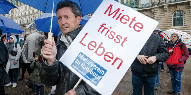 Ein Mann hält ein Plakat mit der Aufschrift "Miete frisst Leben"