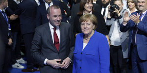 Manfred Weber steht neben Angela Merkel in einer Menschenmenge