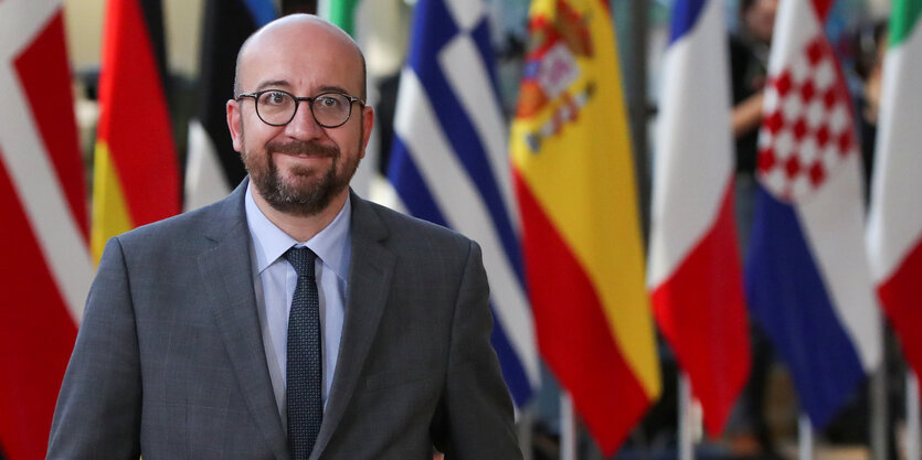 Ein Mann steht vor Flaggen. Es ist der belgische Premierminister Charles Michel