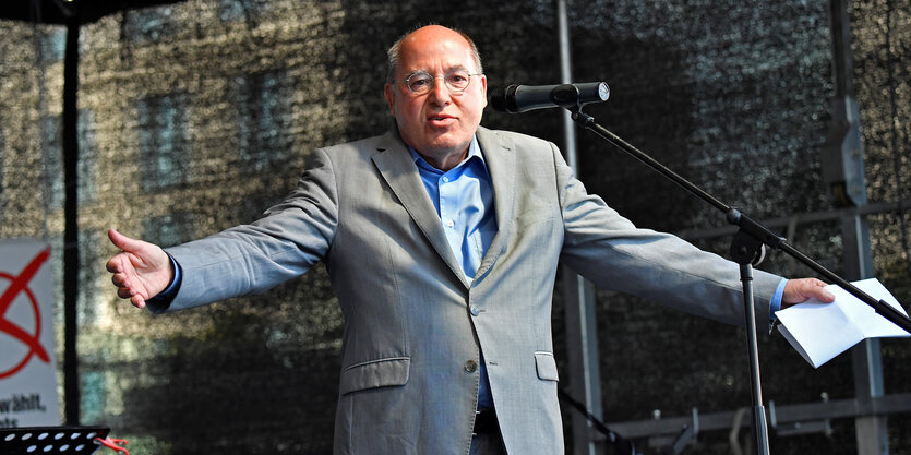 Gregor Gysi breitet auf einer Bühne die Arme aus