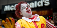 Vor einer McDonalds-Filiale steht ein Mensch, der sich als Zombieversion von Ronald McDonald verkleidet hat
