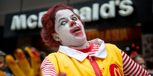 Vor einer McDonalds-Filiale steht ein Mensch, der sich als Zombieversion von Ronald McDonald verkleidet hat
