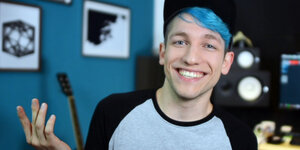 Ein Mann mit blauen Haaren lächelt in die Kamera