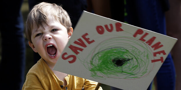 Ein schreiendes Kleinkind hält ein Schild mit den Worten „Save the Planet"“