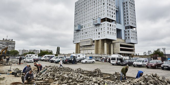 Männer arbeiten auf einer Baustelle vor einem Hochhaus