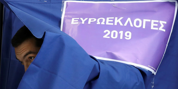 Tsipras guckt unter einer blauen Decke hervor