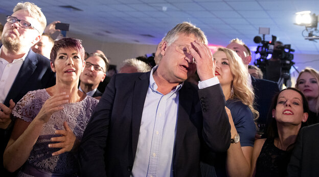 Jörg Meuthen steht auf der AFD-Wahlparty und reagiert auf die ersten Prognosen, in dem er sich die linke Hand vor sein Gesicht schlägt. Um ihn herum stehen Parteigenossen und -Genossinnen, die ebenfalls entsetzt dreinschauen.