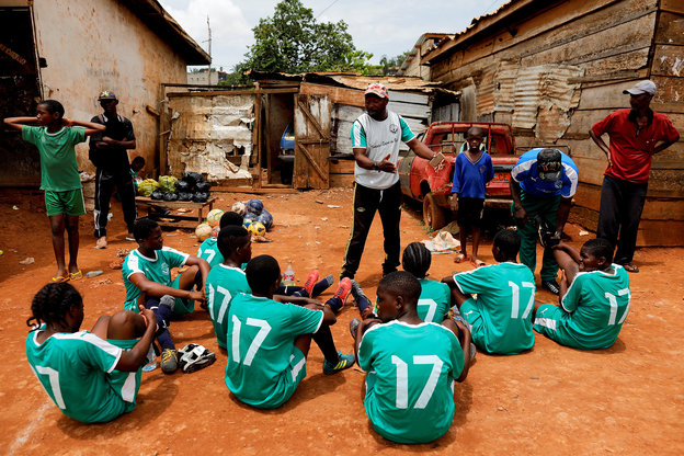 Eine Mädchenmannschaft in Kamerun bekommt vor einem Spiel Anweisungen des Trainers.