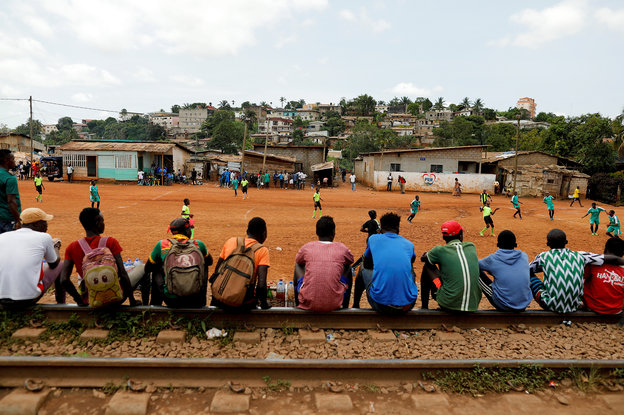 In Yaounde, Kamerun, sitzen Menschen auf Bahngleisen, um bei einem Fußballspiel zuzuschauen.