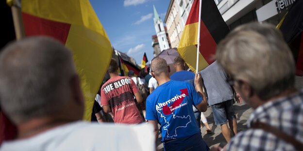 Ein nationalistischer Protestzug in Brandenburg. Ein Mann mit Deutschland-Fahne trägt ein AfD-T-Shirt